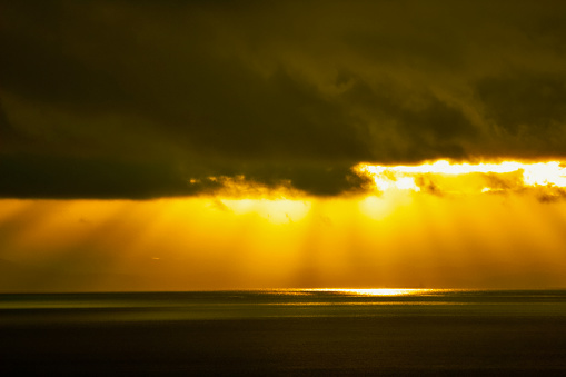 Sun Rays coming through dark clouds over Ocean background
