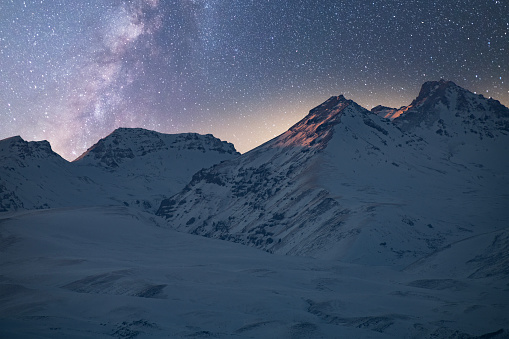 Beautiful night landscape. Snow covered mountains under beautiful bright Milky Way Galaxy.