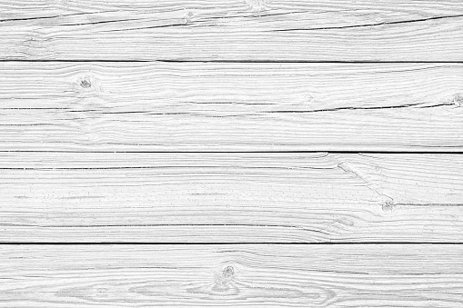 Detail of an old wooden board composed of four planks painted with white color, but weathered and partially peeled. Wood knots, cracks, stains, scratches and other damages are strongly expressed. All planks have a strong clear texture of wood. A wood grain pattern featuring even grains of wood running horizontally across the image. Compounds of the planks are clearly visible.
