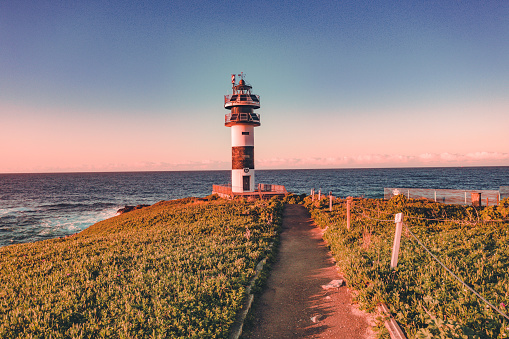 Lonely lighthouse in sunset on the coast of Galicia, Spain. Island of Pancha (Isla Pancha) clote to Ribadeo village