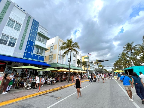 Miami, Florida, USA - January 13, 2023: Nationals and Internationals tourists walking and enjoying a street market at Ocean Drive; looking to buy some pieces of Arts in a sunny summer day at South Beach.