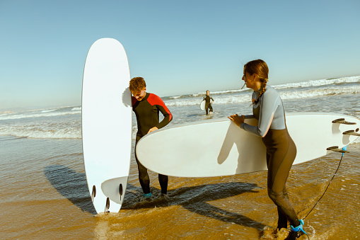 Surfers in wetsuits standing with surfboards and preparing for ride on waves. High quality photo