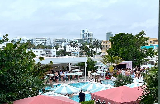Miami, Florida, USA - January 13, 2023: Nationals and Internationals tourists enjoying a pool party at Ocean Drive in a winter day at South Beach.