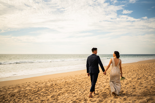 Bride and groom walking through the beach