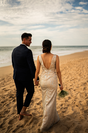 Bride and groom walking through the beach