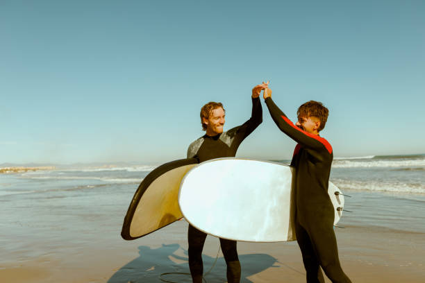 Two surfers greet each other by shaking hands before surfing in ocean. High quality photo
