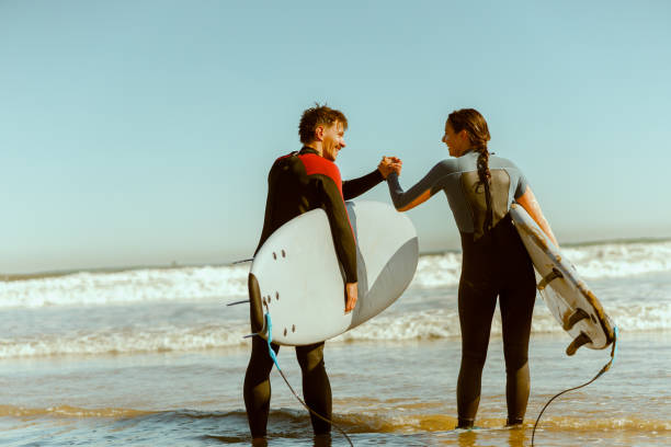 Two surfers greet each other by shaking hands before surfing in ocean. High quality photo