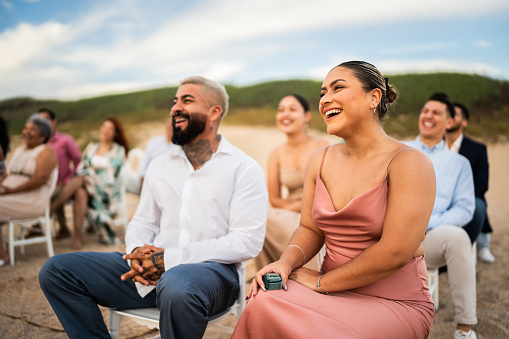 Wedding guests laughing during wedding ceremony on the beach