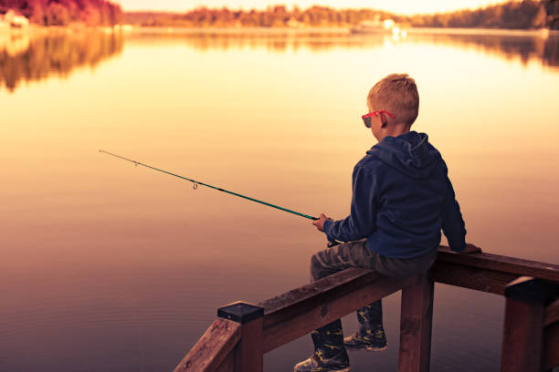 istock Boy fishing on the river at sunset. 1933365324
