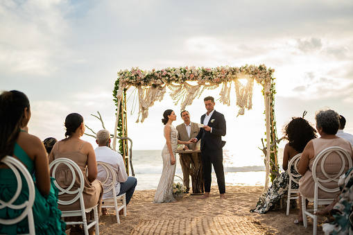 Groom speaking vows to his bride in the wedding ceremony on the beach