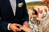 Close-up of a groom putting the wedding ring on her bride in wedding ceremony on the beach