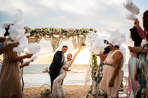 Husband leaning over his wife to kiss her after their beach wedding ceremony
