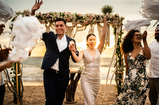A bride and groom walking on the beach