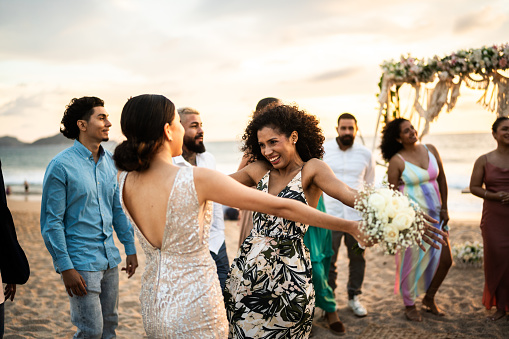 Bride celebrating with her friend at beach wedding party