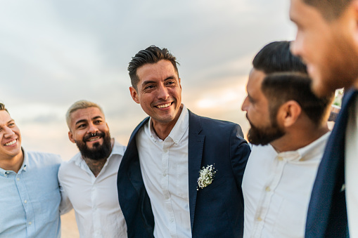 Groom talking with his friends in the wedding party on the beach
