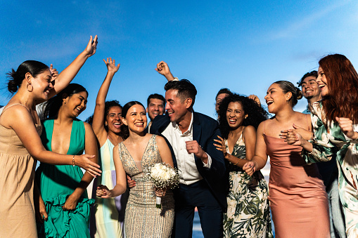 Bride and groom celebrating with their friends on beach wedding party