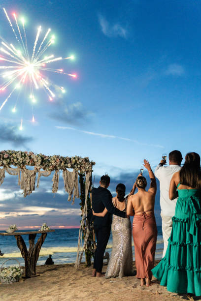 istock Bride and groom watching fireworks with wedding guests on the beach 1933377823