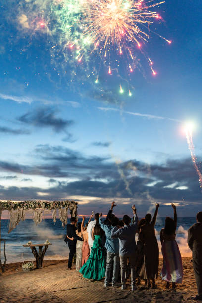 istock Bride and groom watching fireworks with wedding guests on the beach 1933377836