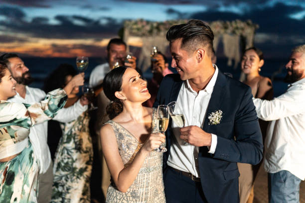 istock Bride and groom toasting on the beach wedding party 1933377870
