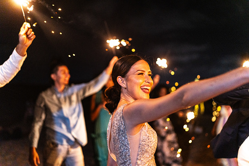 Bride playing with sparklers on the beach wedding party