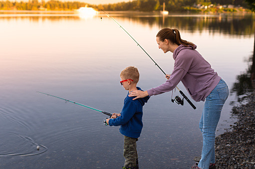 A young boy casting a fly rod at a wilderness lake.