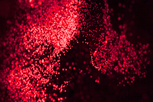 Swirling mass of bright red particles on a dark backdrop.