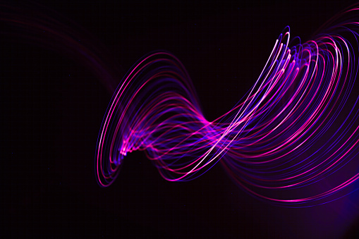 Neon purple light swirls rhythmically on a black backdrop.