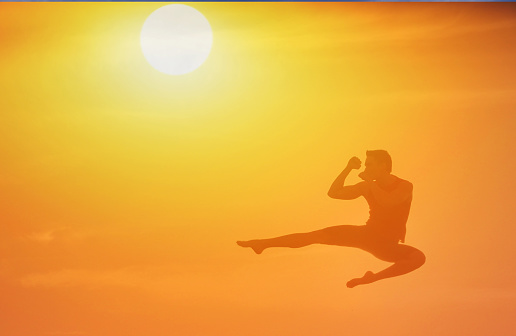 Man doing kick box at sunset.