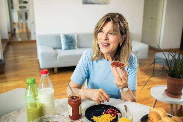 istock Middle-aged woman is having breakfast at home 1933550129