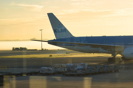 amsterdam, netherlands - 18 October 2022: airplane of klm is docked at gates on the platform of an airport early in the morning with sunset and fog