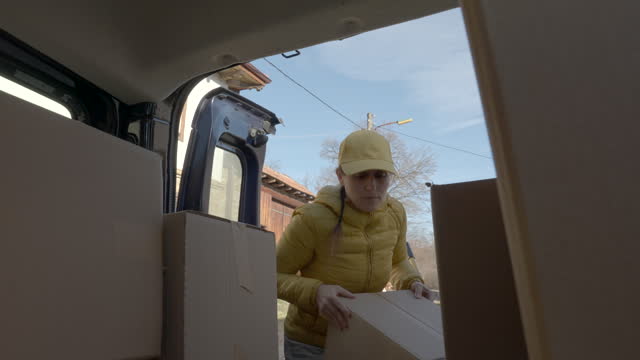 Female courier loads postal parcels for delivery.