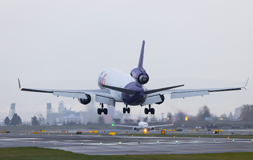 Portland, Oregon, USA - December 1, 2023: A FedEx Express McDonnell Douglas MD-11 lands at PDX with the Vancouver skyline in the background.