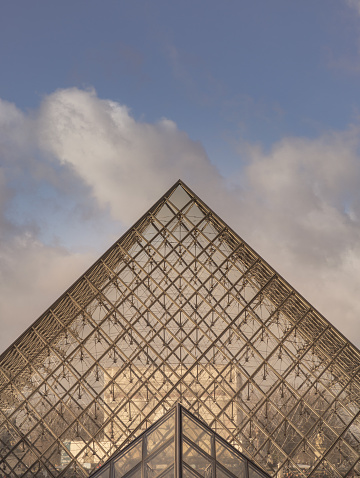 France, Paris - Jan 03, 2024 - Geometrical forms of Glass pyramid with Sky background. Exterior of Louvre pyramid during day time, is one of the world's largest museums in Paris, Space for text, Selective focus.