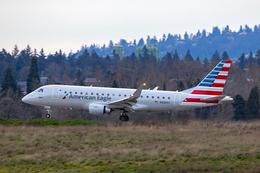 Portland, Oregon, USA - January 1, 2024: An American Eagle Embraer 175 comes in for landing on runway 10R at Portland International Airport.