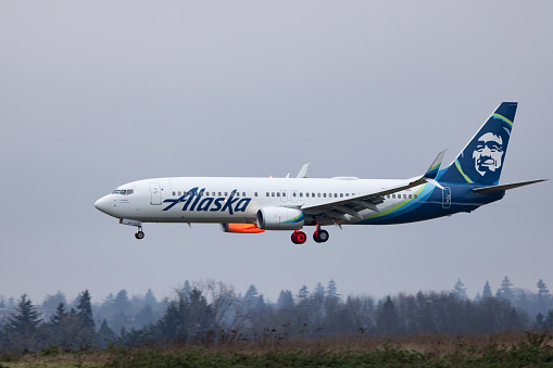 Portland, Oregon, USA - December 31, 2023: An Alaska Airlines 737 landing at dusk at Portland International Airport.