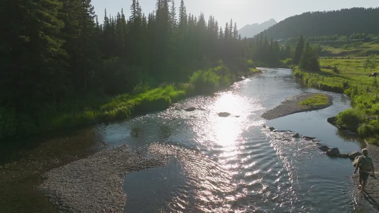 Aerial perspective of man walking up mountain creek in early evening