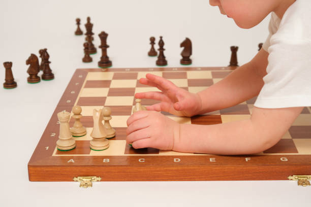 A child is playing chess, studio white background. Baby with chess pieces on a chessboard