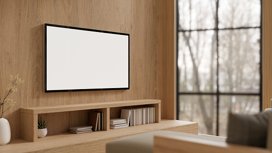A modern white TV monitor mockup on a wooden wall above a wooden cabinet in a modern, expensively furnished living room. 3d render, 3d illustration