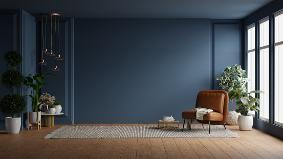 Modern interior of living room with leather armchair on wood flooring and dark blue wall- 3D rendering