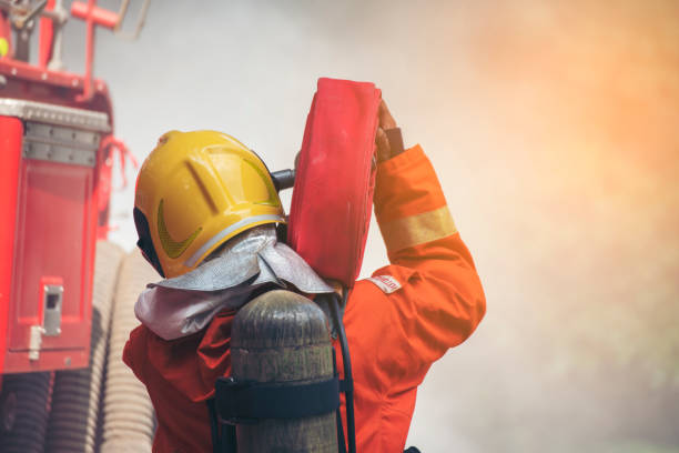 istock Firefighter Rescue training in fire fighting extinguisher. Firefighter fighting with flame using fire hose chemical water foam spray engine. Fireman wear hard hat, safety suit uniform for protection 1933782655