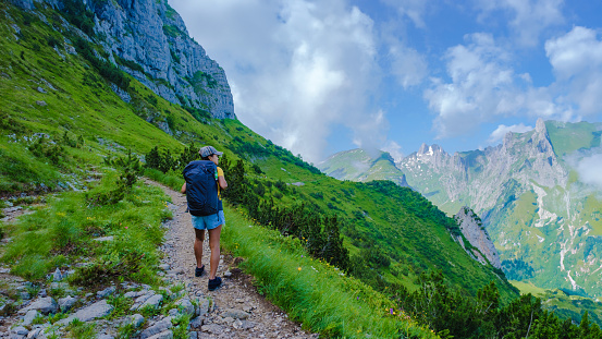 An Asian woman hiking in the Swiss Alps mountains during summer vacation with a backpack and hiking boots. woman walking on the Saxer Lucke path in Switzerland during summer