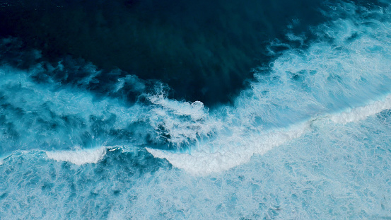 Turquoise ocean sea water white wave pattern splashing deep blue sea. Seascape dark ocean background wave splash on rock. Tropical sea beach in summer seaside outdoor. Water Surface blue wave pattern