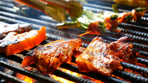 istock BBQ Barbecue grilled meat stick on fire flame with hot charcoal cooking outside. Beef grilling picnic outdoor with smoke bacon spicy sausage for party. Grill pork bbq on fire flame 1933804942