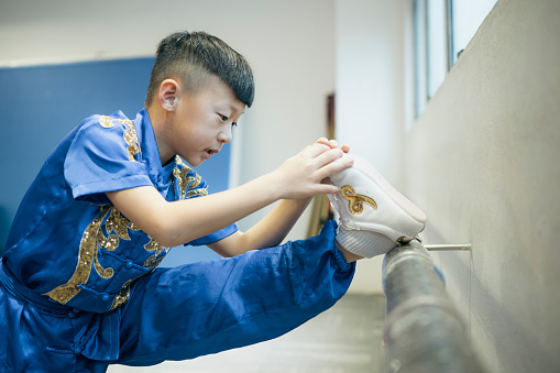 Young Chinese boy stretching before Wushu practice