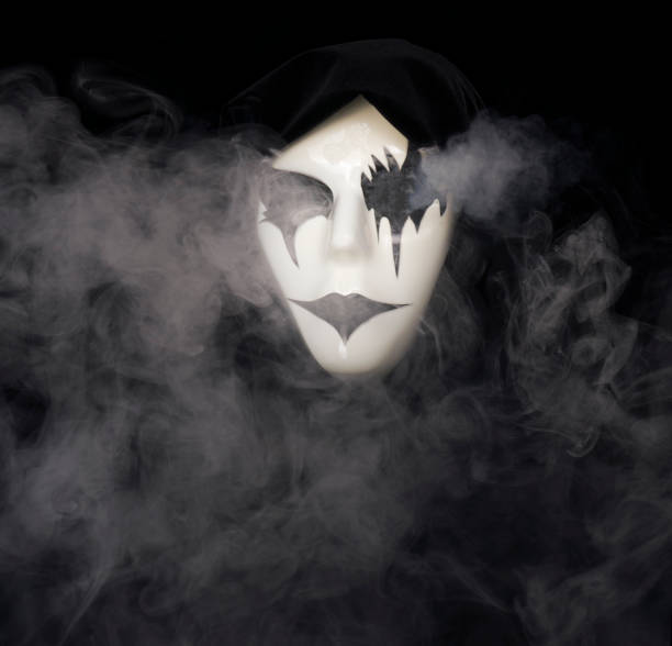 istock Cloak covered hand made mask with smoke pouring from eyes and background 1933896998