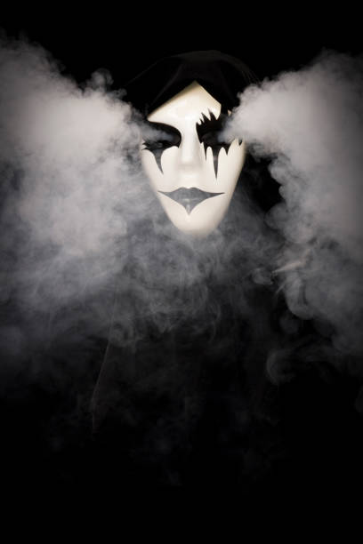 istock Cloak covered hand made mask with smoke pouring from eyes and background 1933897000