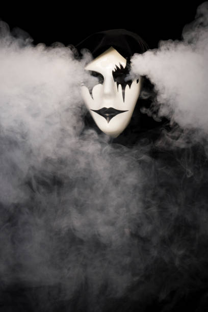 istock Cloak covered hand made mask with smoke pouring from eyes and background 1933897008