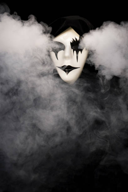 istock Cloak covered hand made mask with smoke pouring from eyes and background 1933897040