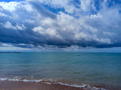 Cumulus clouds over the sea. Dramatic seascape. Waves on the shore. Kyrgyzstan, Lake Issyk-Kul