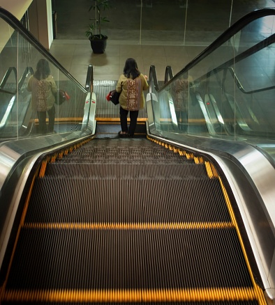 lone woman descending escalator in a hotel